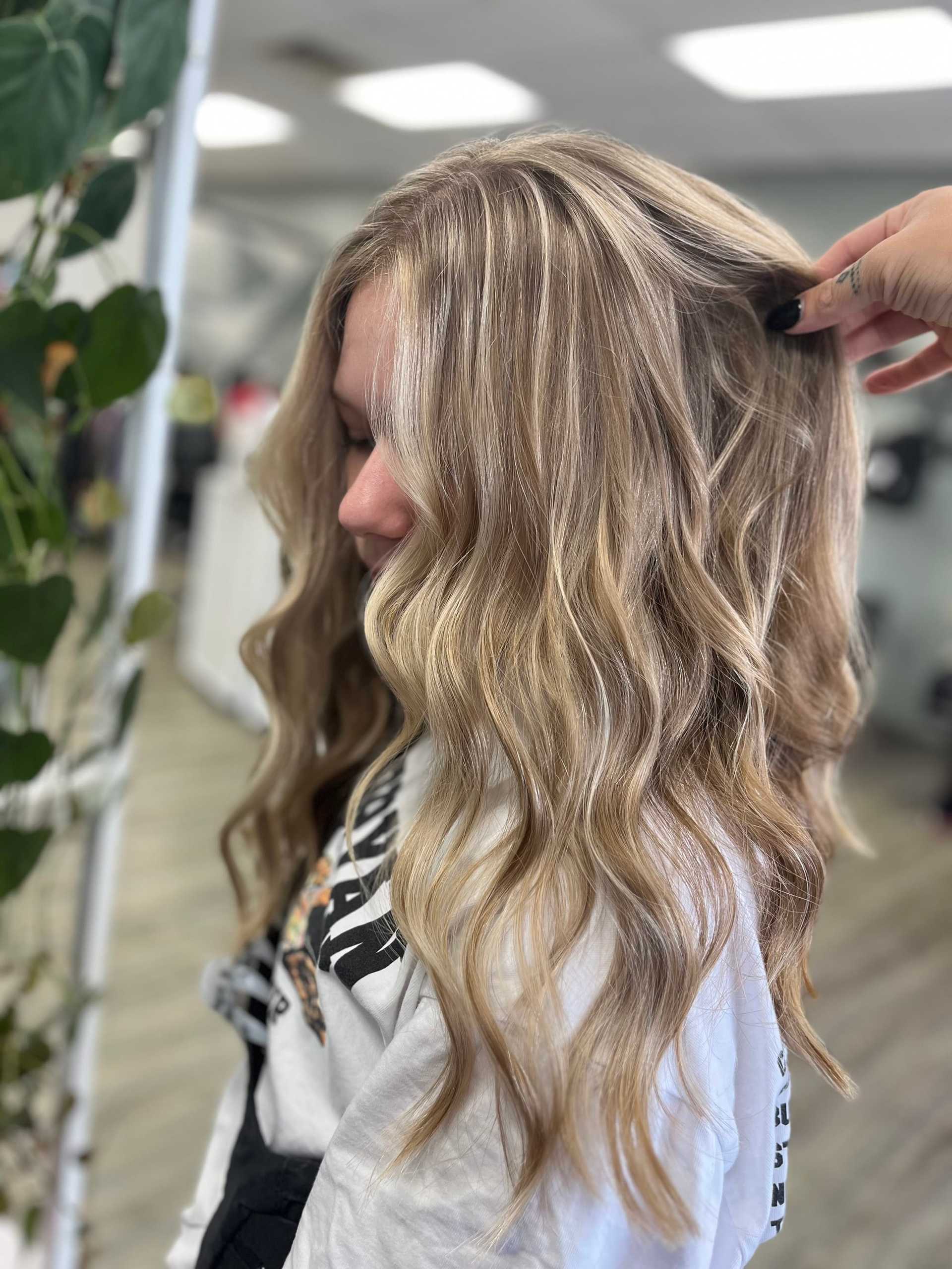 Blonde hair with soft curls highlighted, styled in a salon setting.