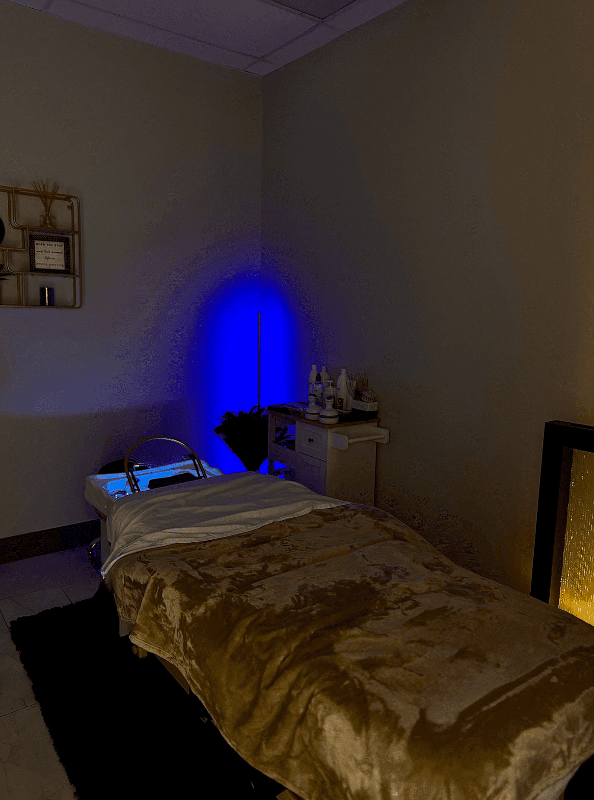 Spa room with massage table, dim lighting, and calming blue accents.