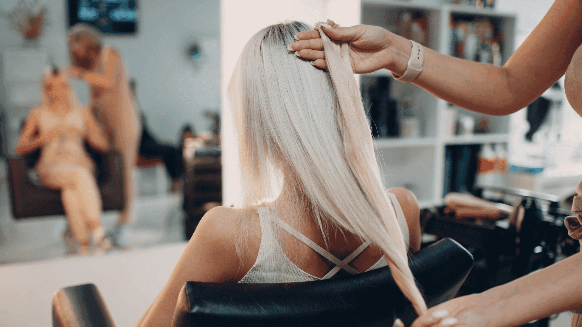 Hairdresser styling long blonde hair in a salon setting.