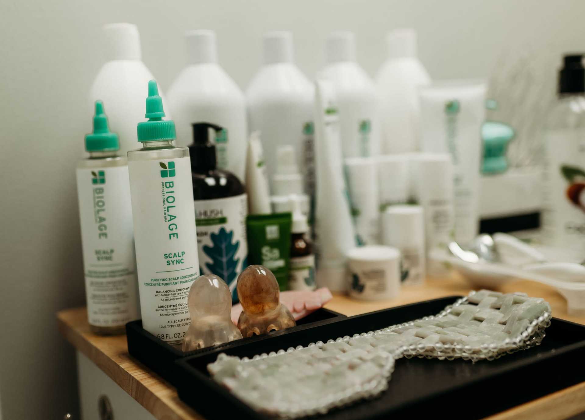 Hair care products and tools displayed on a wooden shelf in a salon setting.